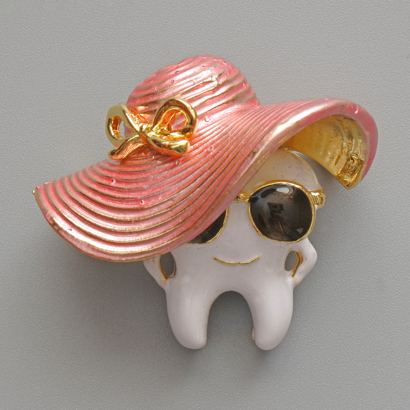 Brooch 'Tooth in a Hat' with white, pink, and black enamel, gold-tone metal 33×30mm